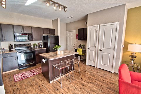 an open kitchen and living room with a wooden floor and a table with chairs